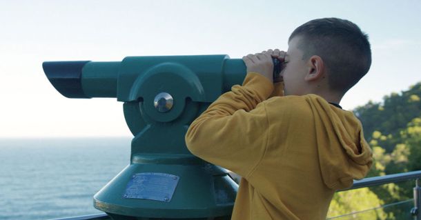 Child looking through a telescope